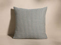 Front view of the Nootka Pillow, featuring a woven cream, teal, and rust geometric motif.