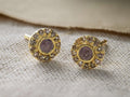 Front view of two round Noressa Earrings with gold settings, central iridescent grayish-purple stones, and light brown pavv© diamonds.