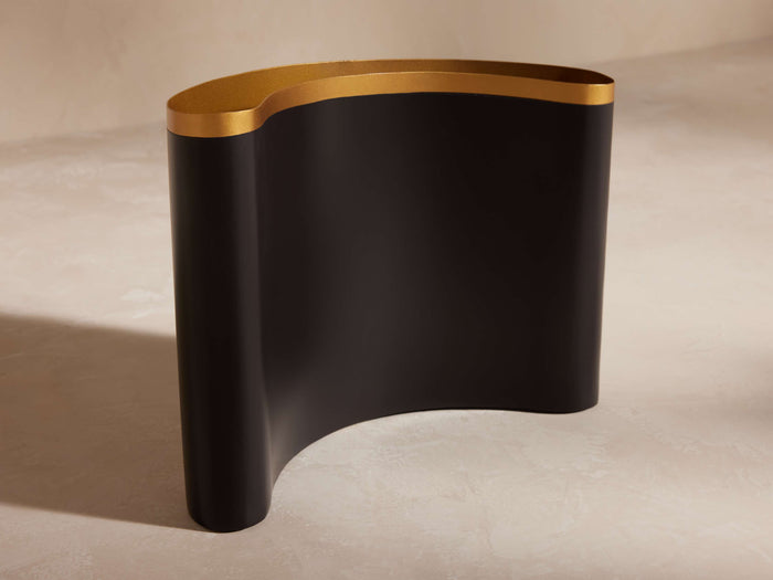 Nouria Abstract Vase: Curved, ebony-finished aluminum vase with a bright brass interior rim, standing upright on a light surface.
