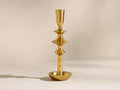 Upright brass-finished Nouria Taper Holder with a distinctive stem featuring three bulbous sections above a round base.