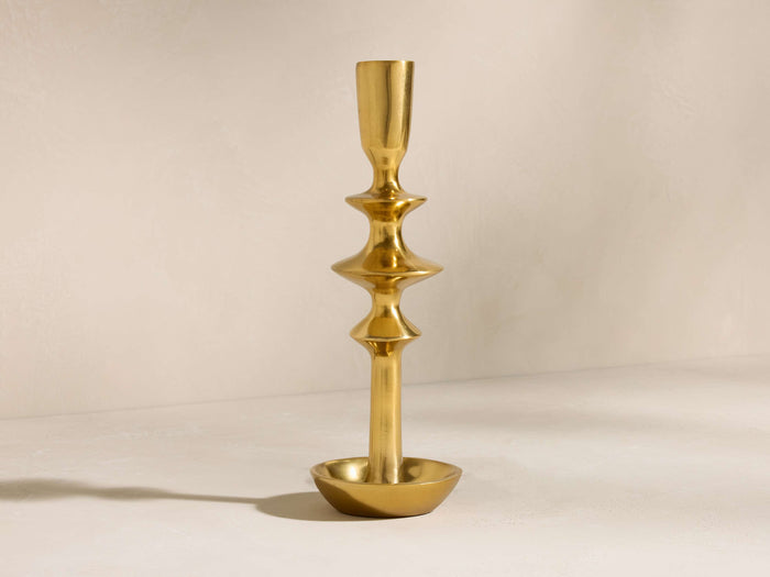 Upright brass-finished Nouria Taper Holder with a distinctive stem featuring three bulbous sections above a round base.