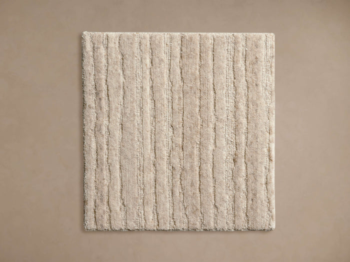 Nova Hand-Knotted Rug Swatch in beige, features a textured, vertical stripe pattern. Square shape on a neutral background.