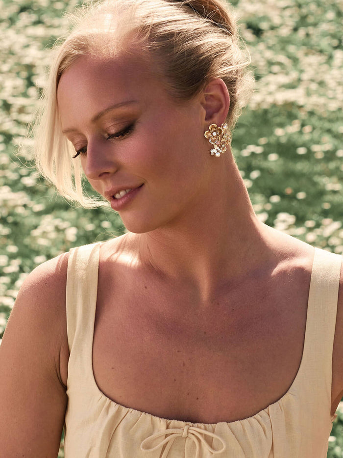 Woman wearing gold earrings with a blurred natural background