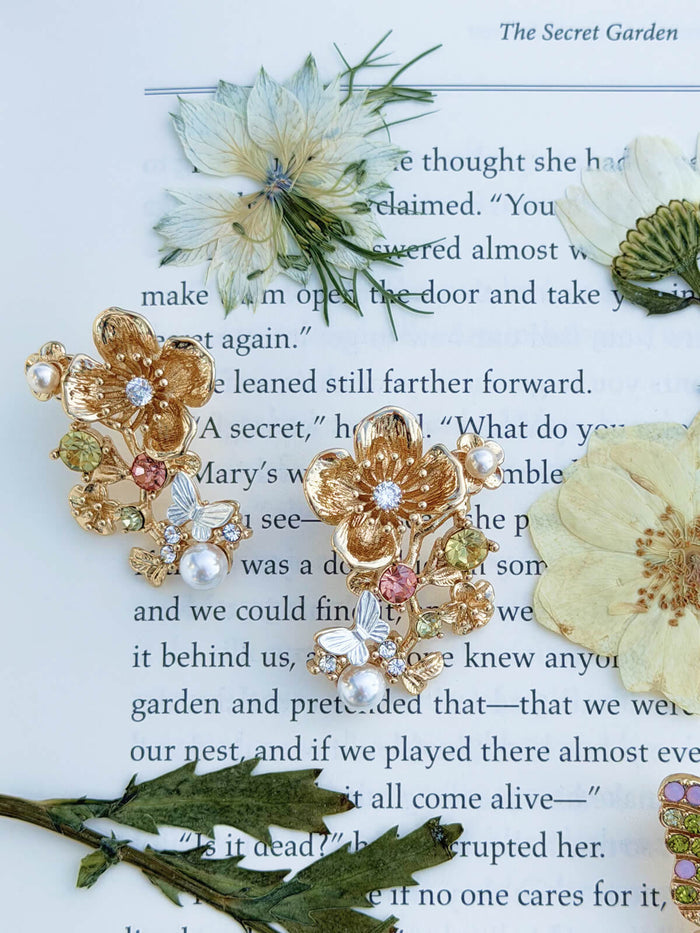 Gold floral earrings with pearls on a page of 'The Secret Garden' book.