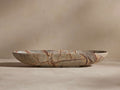 A shallow, oval-shaped stone bowl with marbled brown and beige patterns on a beige background, showcasing its natural texture.