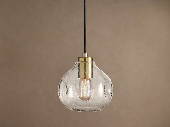 Organic 8" Pendant: Clear, seeded mouth-blown glass shade with brass hardware, black cord, and a glowing Edison bulb.