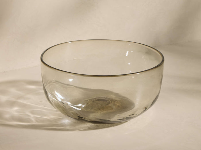 Front view of the smoky clear recycled glass Organic Serving Bowl, featuring its subtly pinched, organic shape.