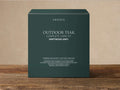 Arhaus Outdoor Driftwood Grey Care Kit box, dark teal with white text, standing upright on a wooden surface against a light wall.