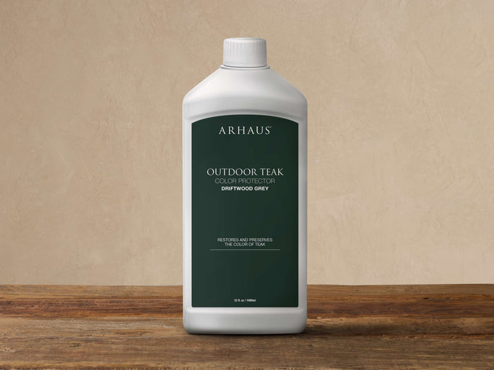 White Arhaus Outdoor Teak Color Protector, Driftwood Grey, 33 fl oz bottle with dark label, on wood.