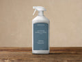 White 33.8 fl. oz. Arhaus Outdoor Marble and Stone Cleaner bottle with dark blue label and white spray top on wood.