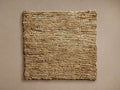 Pearce Rug Swatch, natural tan woven texture, rectangular shape, shown flat on a neutral taupe background.