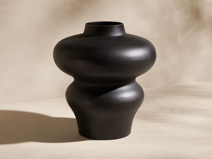 Pelle Vase. Matte ebony-finished aluminum vase with a unique bulbous shape: wide top, narrow middle, flaring base, on light ground.