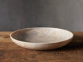 Petra Century Marble Bowl with golden streaks and veins on ivory stone, resting on a wooden surface against a neutral background.