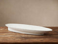 Planes Centerpiece Bowl: Elongated white stucco-finished bowl with textured surface, on a rustic wooden table.