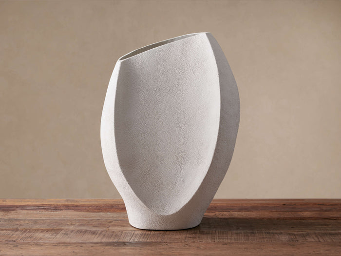 White stucco Planes Vase, abstract angular shape with an asymmetric opening, standing on a rustic wooden surface.