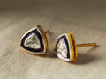 Polki Diamond Stud Earrings featuring triangular-shaped diamonds set in gold with dark accents, resting on a textured surface.