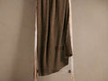 A dark brown textured blanket draped over a rustic wooden ladder against a plain beige background.