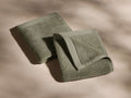 Two neatly folded gray-green towels with visible texture, placed on a smooth, light beige surface with soft shadows.