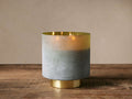 Retreat Olive Fig Candle in frosted glass, fading grey-green to yellow, with an antique brass base & lit wicks.