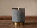 Retreat Spiced Vanilla Oakwood Candle: lit flame, dark gray frosted glass, antique brass base, on rustic wooden surface.