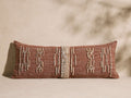 Reyes Outdoor Pillow, rectangular terracotta pillow with textured cream jacquard vertical patterns, lying on a light surface.