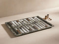 Rhodes Backgammon Set with marble board, brass and aluminum pieces. Includes four brass dice, displayed on a beige surface.