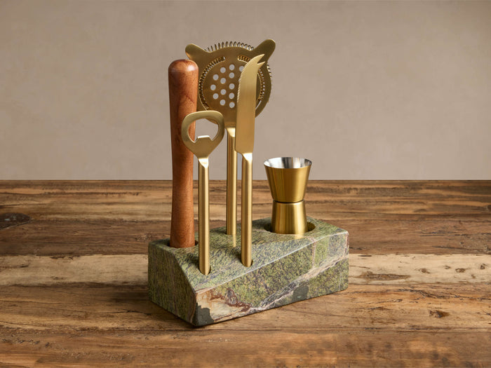 Rhodes Bar Tool Set: acacia wood muddler, gold bottle opener, strainer, knife, peg measure in green marble stand.