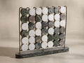 Front view of the Rhodes Four in a Row game, featuring an antique brass rack and dark green marble base, with round white, green, and brown/grey marble game pieces inserted.