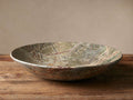 Rhodes Marble Bowl, wide and shallow, crafted from natural greenish-gray marble with striking reddish-brown and dark veins, on wood.