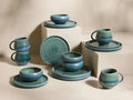 Full view of the blue-green reactive glaze Rhoswen Dinnerware with Cereal Bowls (Set of 16), displayed on neutral blocks.