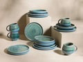 Full set of blue-green reactive glaze Rhoswen Dinnerware With Pasta Bowls, stacked and arranged on different levels.