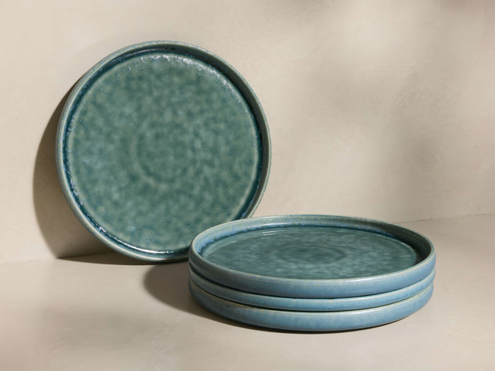 Teal-green Rhoswen Salad Plates, one standing upright, three stacked, showing reactive glaze and tonal variations.
