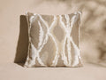 Riah Outdoor Pillow. Square beige boucl?? pillow with abstract white geometric patterns. Front view on light background.