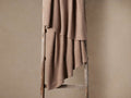 Warm taupe Rib Knit Throw with visible ribbed detailing, draped casually over a rustic wooden ladder against a light brown wall.