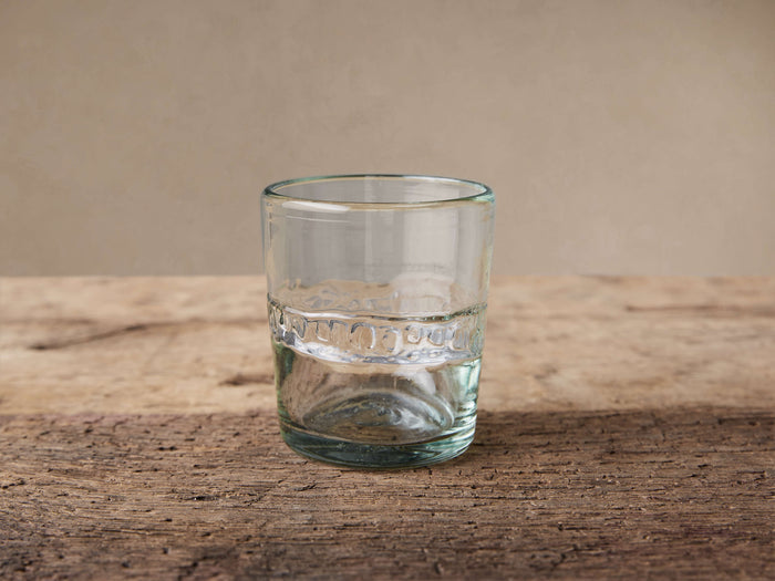 Ribbon Clear Double Old-Fashioned Glass on rustic wood. Recycled clear glass has a textured ribbon band, partially filled.