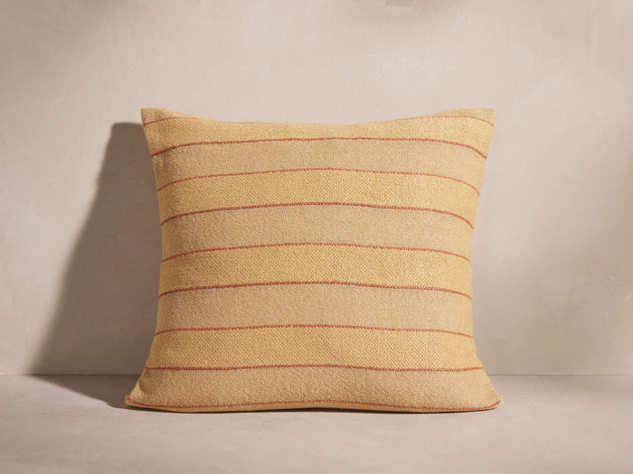 Rory Pillow: Square, light yellow textured pillow with slim reddish-brown horizontal stripes, standing on a neutral surface.