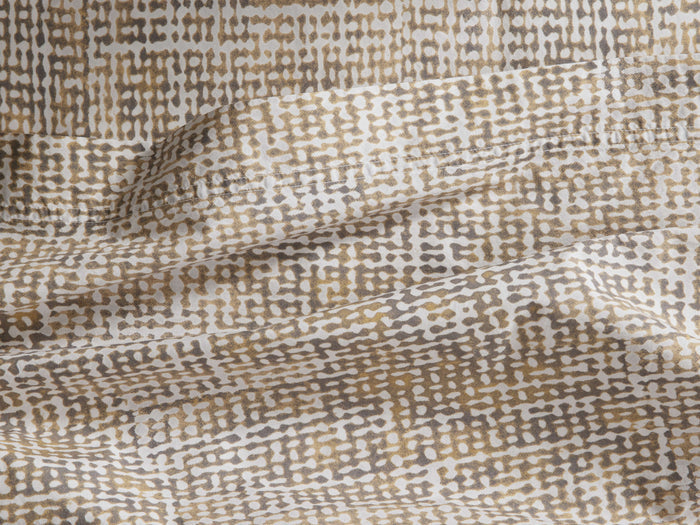 Roula Flat Sheet, close-up of folded fabric with abstract white, brown & gold mottled pattern. Visible stitched hem.