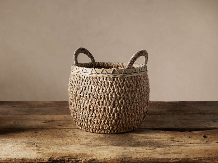 Round Entry Basket in Natural, handwoven seagrass, textured, with two top handles, on a rustic wooden table.