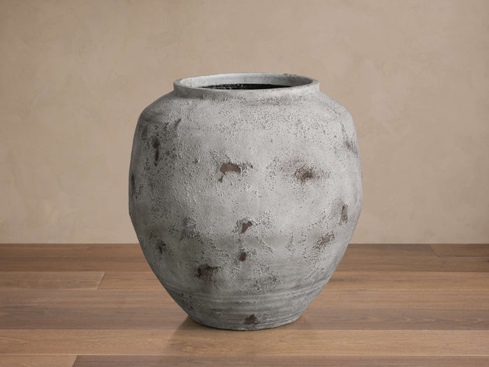 Large, rounded Rustic Grey Vessel, a distressed light grey terracotta vase with dark brown accents, standing on a wooden floor.