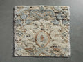 Sadie Hand-Knotted Rug Swatch on a gray surface, showcasing soft blue, beige, and cream colors with an abstract pattern.
