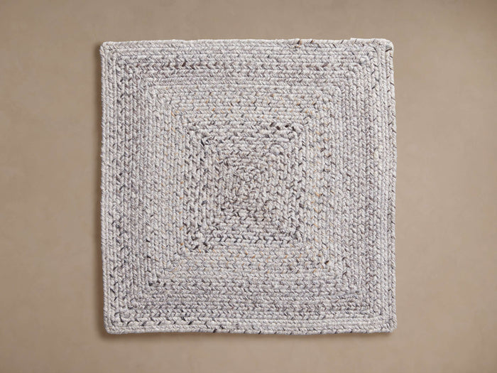 Sansa Outdoor Rug Swatch: A light grey and off-white rectangular braided rug swatch with dark flecks, seen from above.