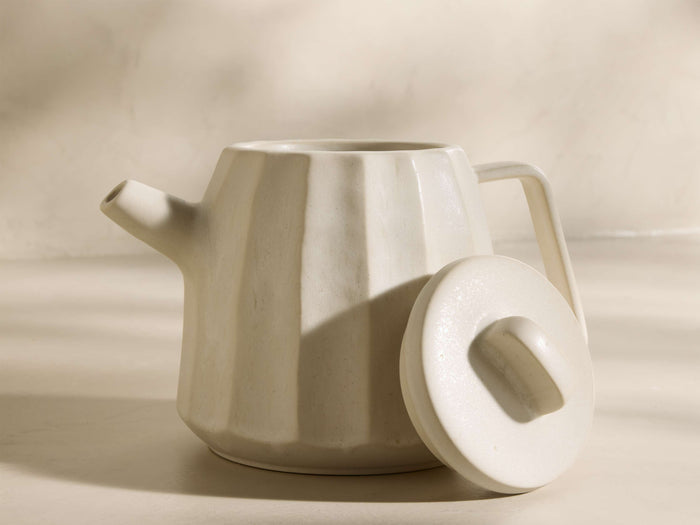 Front view of the cream Saskia Tea Pot, featuring vertical textured ridges, with its matching round lid placed beside it.