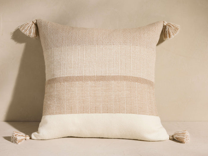 Savera Pillow: square, horizontally striped in beige, cream, and tan, with tassels on each corner.