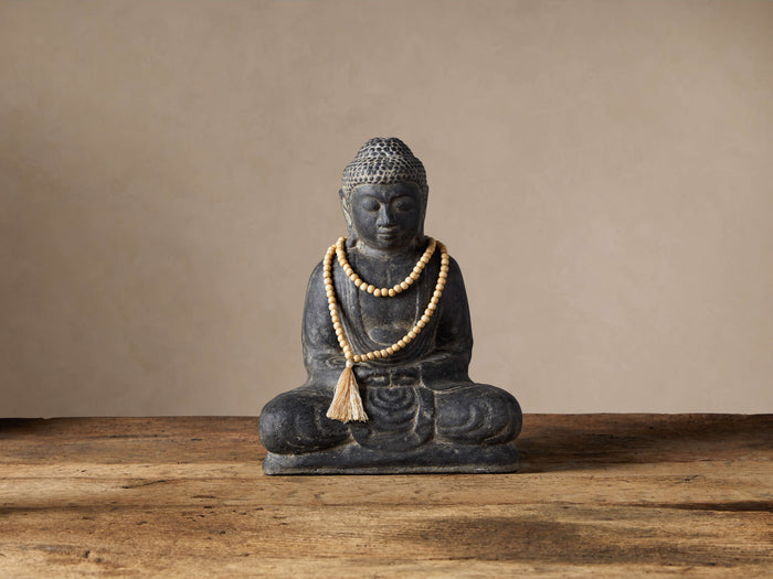Seated Buddha statue made of dark gray cast stone with a natural finish, wearing light wood prayer beads and tassel.