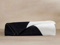 Folded Serna Beach Towel in Meteorite color, half black and half white, with a curved diagonal dividing line.