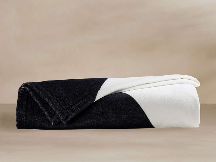 Folded Serna Beach Towel in Meteorite color, half black and half white, with a curved diagonal dividing line.