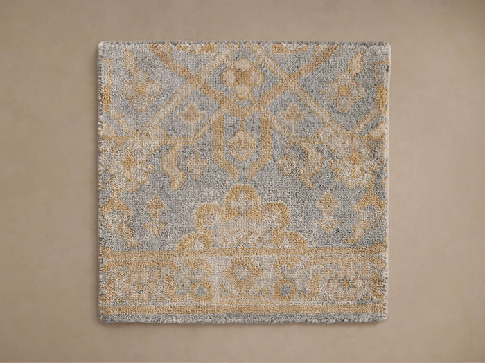 Sienna Hand-Knotted Rug with intricate blue and gold pattern, featuring geometric and floral designs, on a beige background.