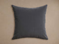 Dark charcoal gray Sienna Outdoor Pillow with a velvety texture, centered on a warm, neutral background.