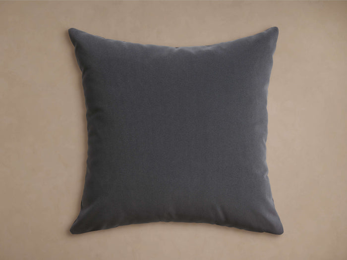 Dark charcoal gray Sienna Outdoor Pillow with a velvety texture, centered on a warm, neutral background.