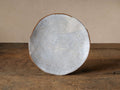Skye Salad Plate, irregular organic shape, white/gray reactive glazed stoneware with dark brown trim, standing upright on rustic wood.